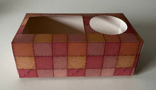 A Period Box with a rectanguular opening on the left side and a round opening on the right side. The pattern is various shades of organge and amber sqaures stitched together like a quilt. The box is called Let's Talk About it.